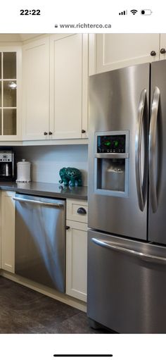 a kitchen with stainless steel appliances and white cupboards, including a refrigerator freezer