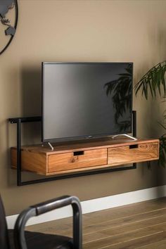 a flat screen tv sitting on top of a wooden shelf next to a wall mounted plant