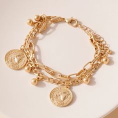 Layered chain bracelet with coin charms and ball charms. Approx Circumference: 8" + 2" extension Coin Charm Bracelet, Layered Chain, Layered Chains, Brass Gold, Chain Bracelet, Gold Bracelet, Coin, Gold Plate, Charm Bracelet