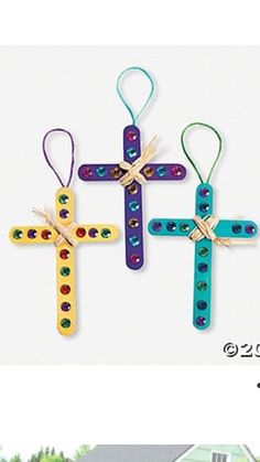 three wooden crosses are hanging on the side of a house and one is decorated with beads