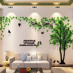 a living room with white furniture and green trees on the wall above it is a coffee table