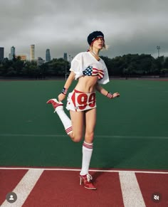 a woman is standing on a field with her leg in the air while wearing an american flag outfit