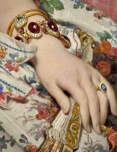 a close up of a woman's hand with bracelets and rings on it