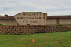 the sign for minnesota's correctional facility sits in front of a grassy field and brick wall