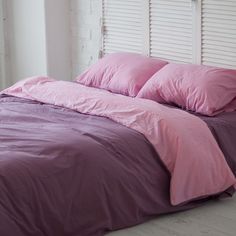 a bed with pink sheets and pillows in a room