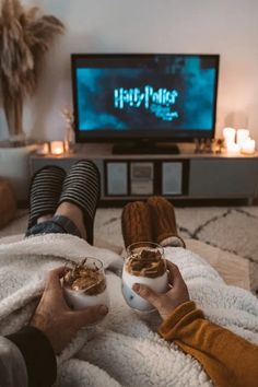 two people are sitting on the floor with their feet up and holding cups in front of them