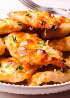 a white plate topped with cheesy chicken wings covered in cheese and parsley