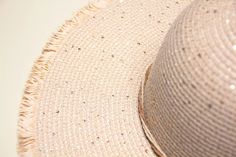 a close up of a straw hat on a white table with sequins and beads