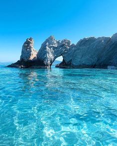 the water is crystal blue and clear with rocks sticking out of it's sides