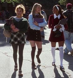 three girls in school uniforms are walking down the street