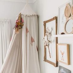 a canopy bed in the corner of a room with pictures on the wall behind it