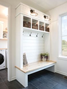 a white bench with baskets on it in front of a washer and dryer