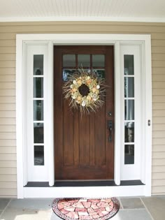 a front door with a wreath on it and an entrance mat in the foreground