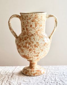 a white and brown vase sitting on top of a table