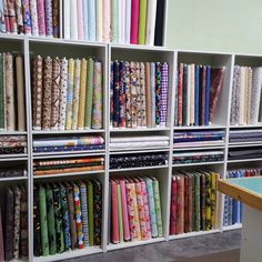 the shelves are full of different colored fabrics