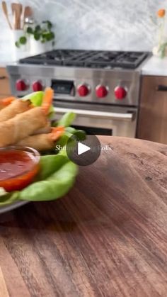 a plate filled with vegetables and dipping sauce on top of a wooden table next to an oven