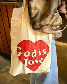 a woman holding a tote bag with the words god's love printed on it