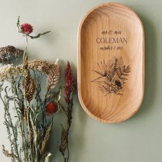 a wooden plate with a wedding date on it next to dried flowers and greenery