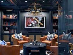 a living room filled with furniture and a chandelier above a table in front of bookshelves