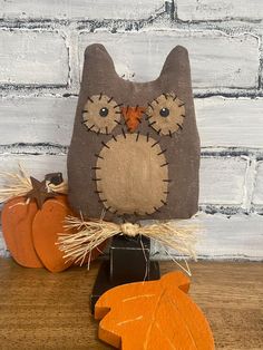 an owl pillow sitting on top of a wooden table next to pumpkins and hay