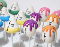 there are many cake pops with different colored icing on them and measuring tape in the background