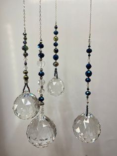 three glass beads hanging from chains on a wall