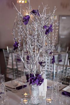 the centerpieces are decorated with purple flowers and crystal beads, along with candles