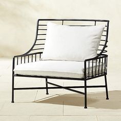 a white pillow sitting on top of a black metal chair with a white seat cushion