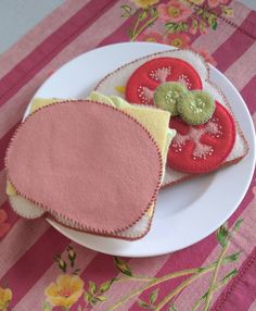 some cookies are on a white plate with pink and yellow cloth around the edges, along with a green cookie