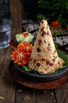 a plate topped with rice and vegetables on top of a wooden table next to a glass of water