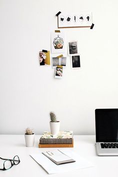 an open laptop computer sitting on top of a white desk next to a potted plant