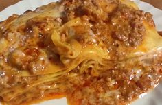 a white plate topped with lasagna casserole covered in meat and cheese