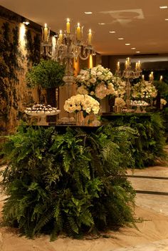 a table with flowers and candles on it in the middle of a room filled with people