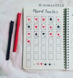 a notebook with playing cards on it next to a red pen and black marker,