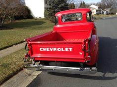 an old red chevrolet truck is parked on the street