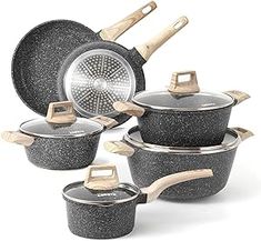 an assortment of granite pots and pans with wooden handles, including one holding a spatula