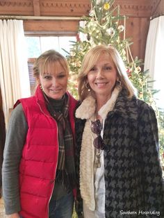 two women standing next to each other in front of a christmas tree