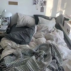 an unmade bed with blankets and pillows on top of it in a small room