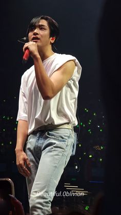 a young man standing on top of a stage holding a red object in his hand