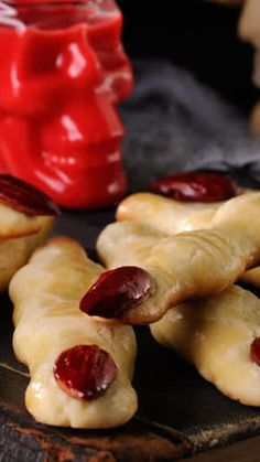 several pastries with jelly on them sitting on a wooden board next to a jar of jelly