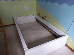 an empty bed frame in a room with blue and green paint on the wall behind it