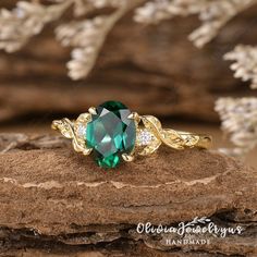 a green ring sitting on top of a wooden log next to some white flowers and leaves