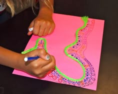 a woman is drawing on a piece of paper with colored crayons and markers