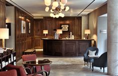 the front desk of a hotel lobby with chairs and lamps on either side of it