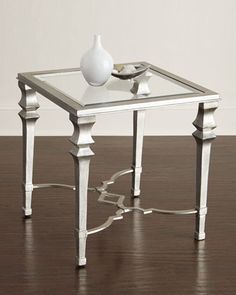 a white vase sitting on top of a table next to a glass topped end table