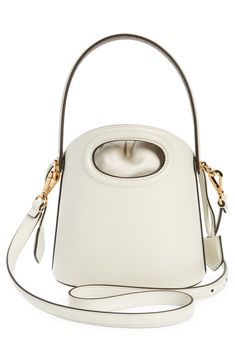 A dipped topline and oval cutout showcase the encased drawstring pouch of this structured leather bucket bag furnished with a top handle and removable strap. Drawstring closure Top carry handle; removable, adjustable crossbody strap Striped-twill lining Structured silhouette with flat base and protective metal feet Leather Imported Designer Handbags Designer White Bucket Bag With Top Carry Handle, Designer Cream Bucket Bag With Detachable Handle, Cream Bucket Bag With Detachable Strap For Evening, White Bucket Bag For Evening, White Leather Bucket Bag With Handle Drop, Cream Leather Bucket Bag For Evening, White Evening Bucket Bag With Top Handle, Cream Bucket Bag With Handle Drop, Cream Bucket Bag With Detachable Handle For Evening