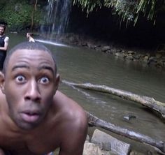 two men are in the water near a waterfall