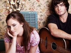 a man and woman are sitting next to each other with guitars in front of them