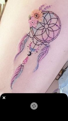 a woman's thigh with a dream catcher tattoo on it