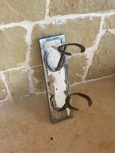 an old pair of scissors hanging on a hook in front of a stone brick wall